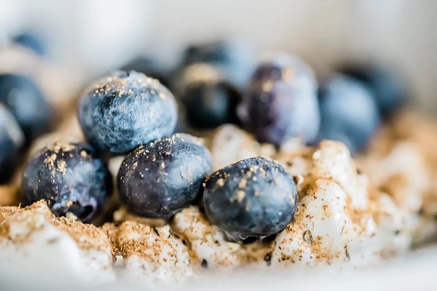 A mouthwatering close-up of blueberries sprinkled over a cereal breakfast, showcasing vivid textures.