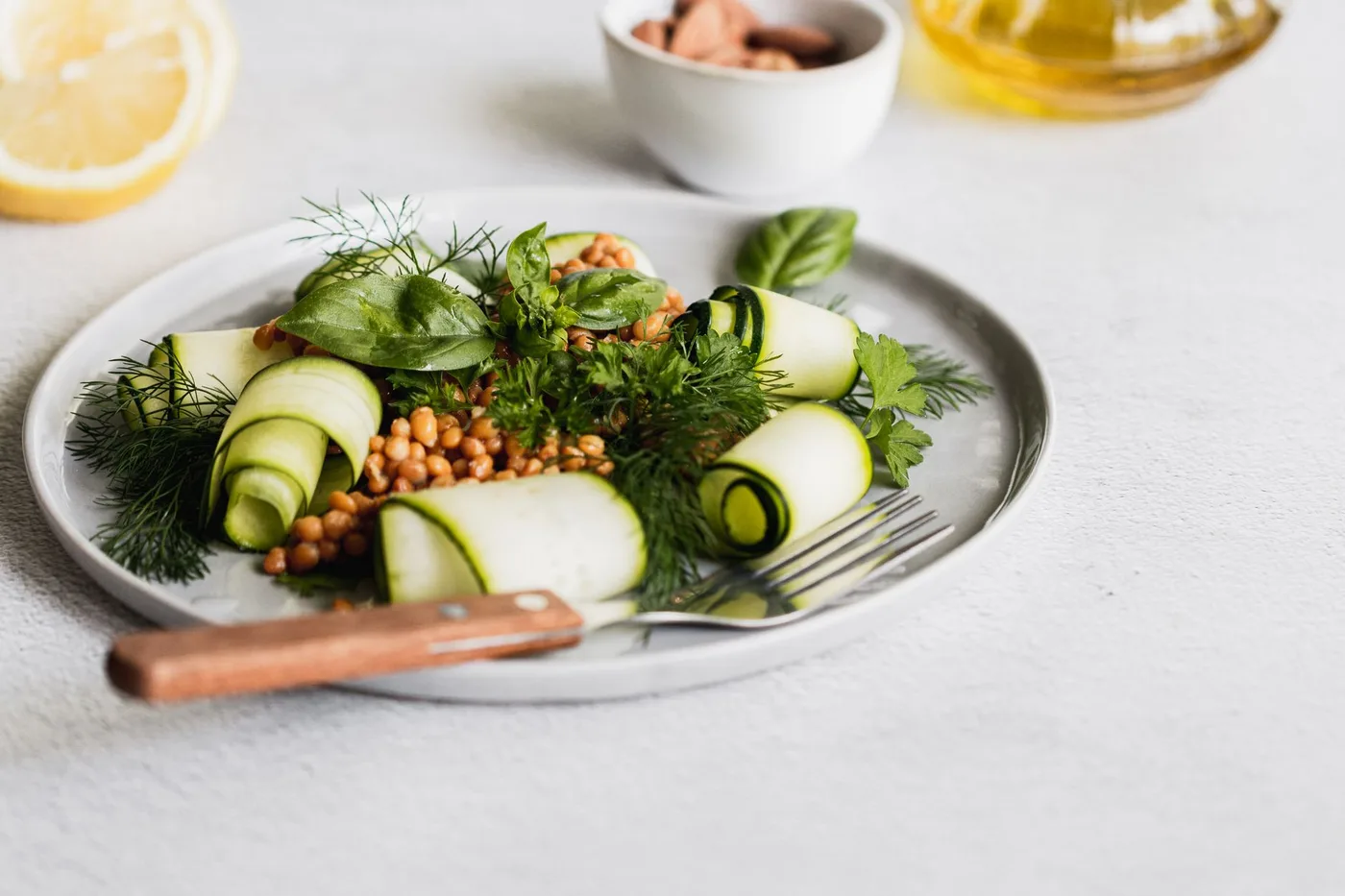 Healthy zucchini and lentil salad with fresh herbs on a ceramic plate.