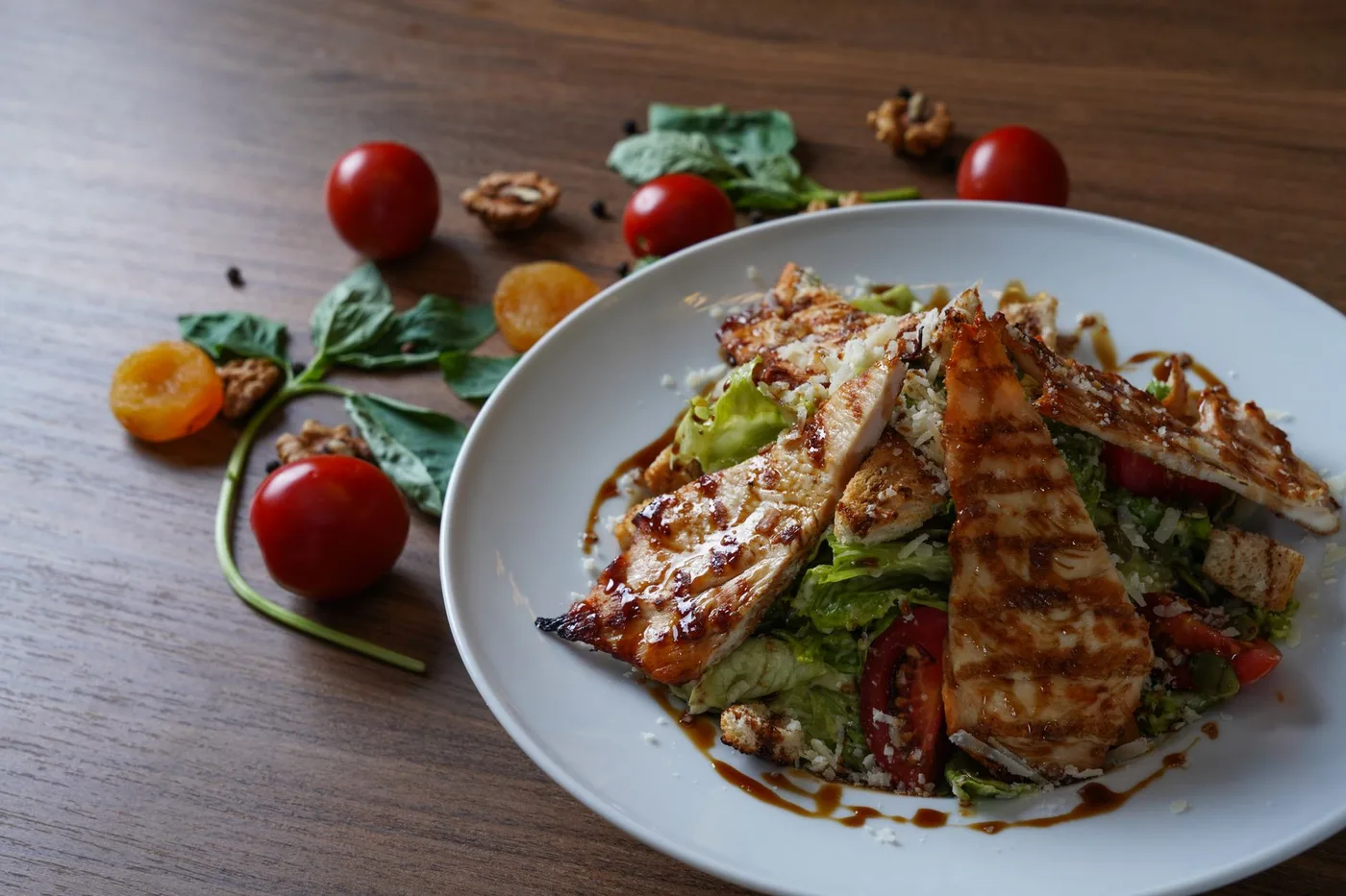 Delicious grilled chicken salad served with fresh tomatoes and walnuts on the side.