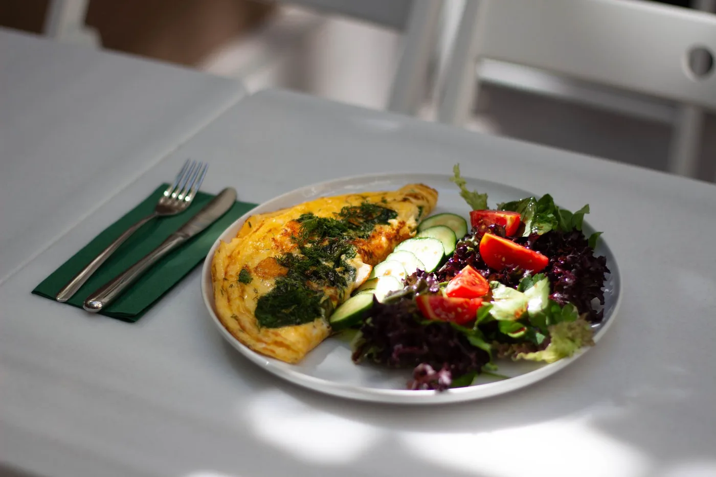 Delicious omelette accompanied by a fresh salad on a white plate, perfect for a healthy meal.