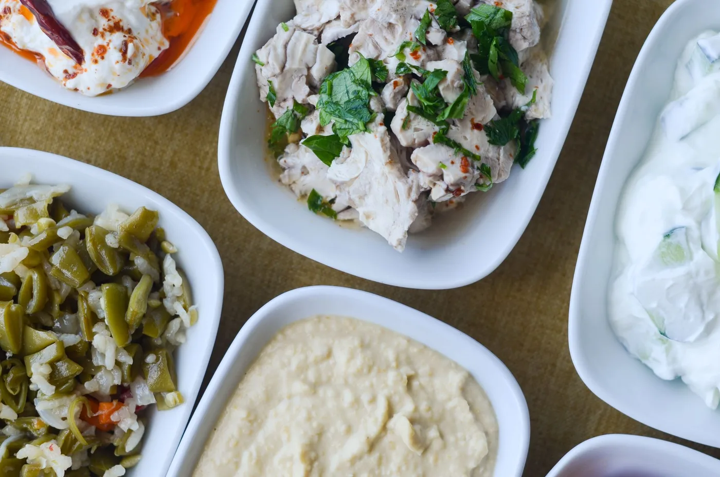 An appetizing assortment of Mediterranean dishes served in white bowls, showcasing diverse flavors.