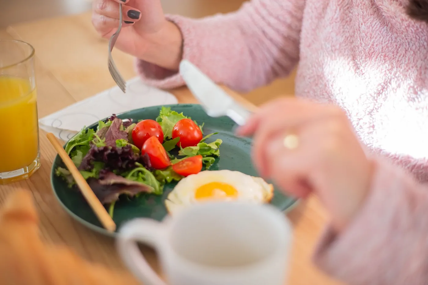 Enjoy a nutritious breakfast with greens, fried egg, and fresh orange juice for a healthy start to your day.