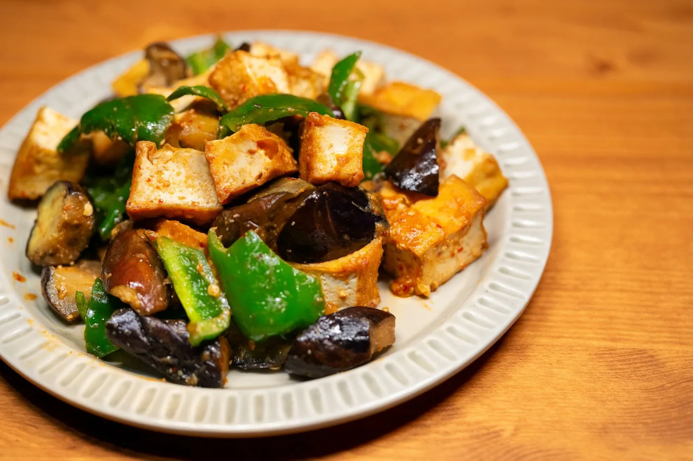 Delicious stir-fried tofu with eggplant and bell peppers served on a plate.