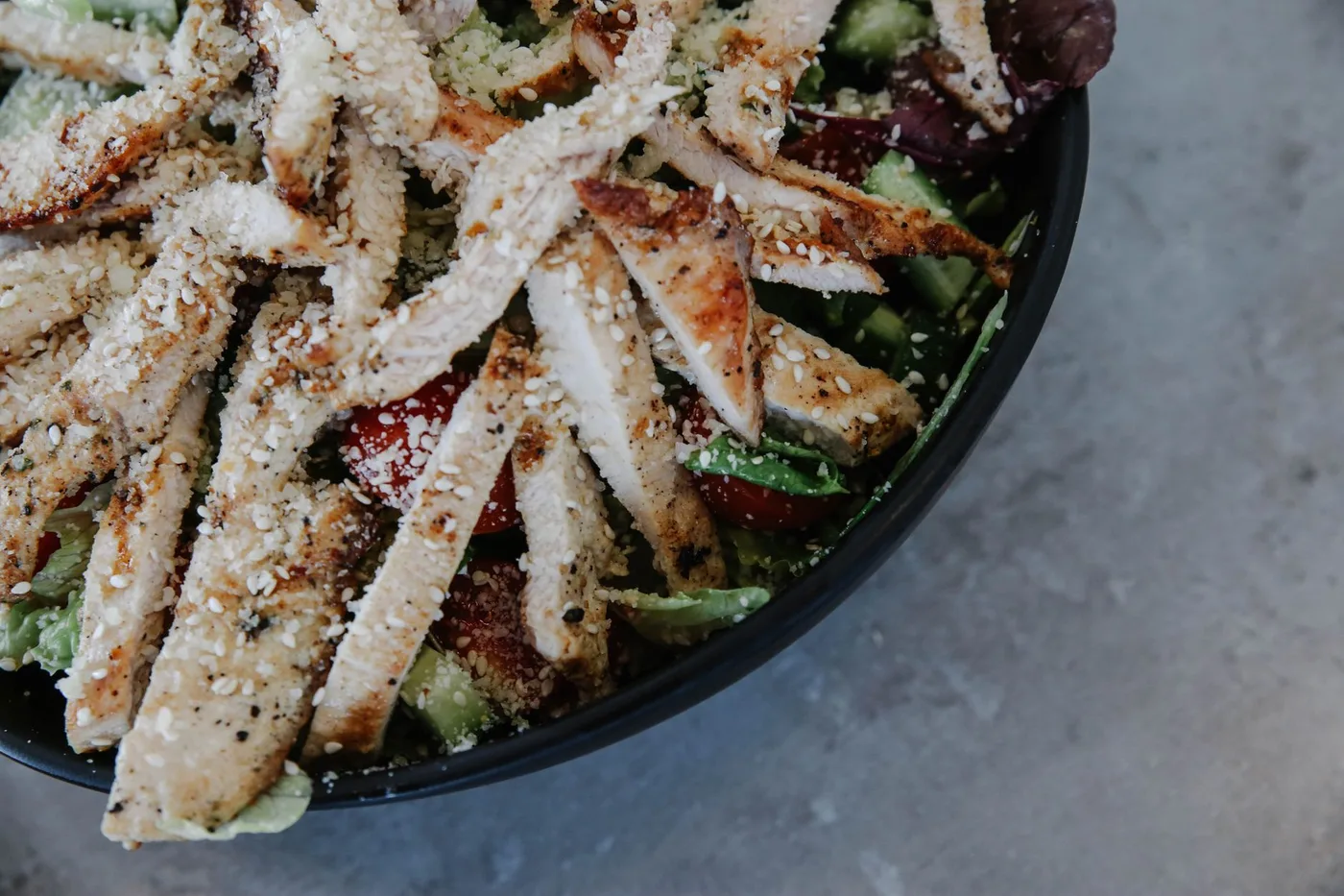 Delicious grilled chicken salad with fresh vegetables and sprinkled seeds.