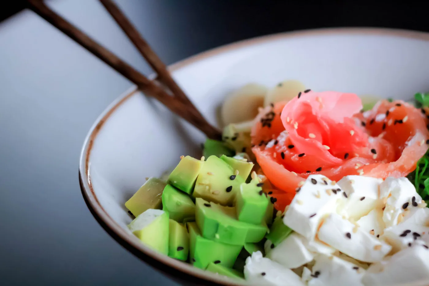 Close-up of a nutritious bowl with salmon, avocado, feta, and greens—perfect for healthy eating inspiration.
