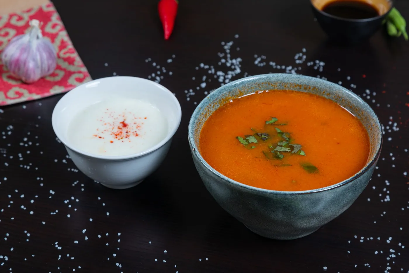 A close-up of flavorful tomato soup and creamy yogurt soup on a dark background.