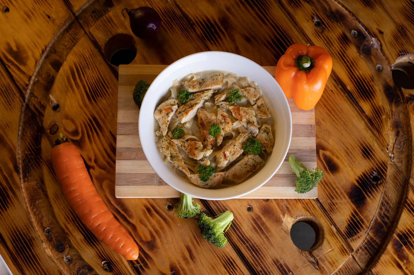 Top view of a rustic chicken and vegetable meal in a white bowl, perfect for healthy dining.
